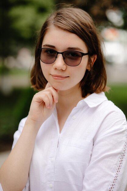 Kobieta w okularach przeciwsłonecznych i białej koszuli z napisem miłość.