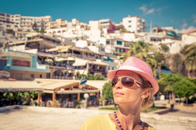 Kobieta w okularach przeciwsłonecznych i różowym kapeluszu na tle europejskiego miasta