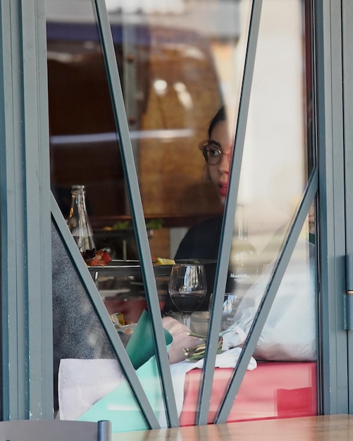 Zdjęcie kobieta w okularach widziana przez okno siedząca w restauracji