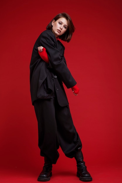 Kobieta w oversize czarnym garniturze z topem na czerwonym tle Fryzura Bob Studio Shot Rebel classic