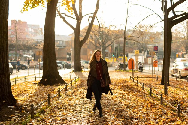 Zdjęcie kobieta w pełnej długości stojąca w parku jesienią