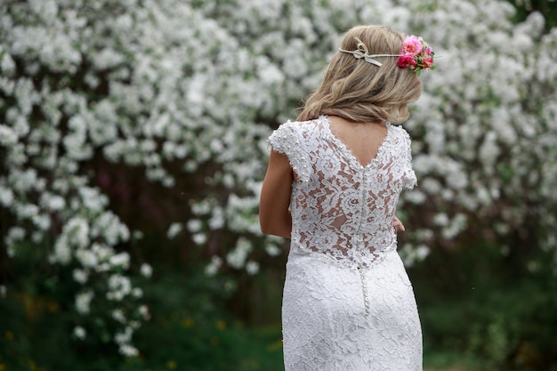 Kobieta w pięknej długiej koronkowej sukni w kwitnącym wiosennym ogrodzie. panna młoda w pobliżu kwitnących drzew na zewnątrz