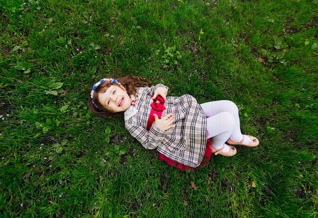 Kobieta w pięknej sukience leży na trawniku i uśmiecha się szczerze