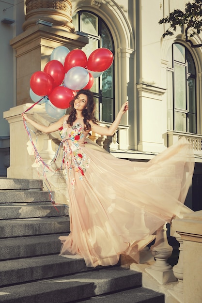 Kobieta w pięknej sukni z dużą ilością kolorowych balonów