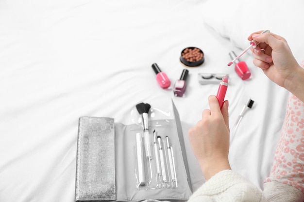 Kobieta w piżamie nakładająca makijaż na swoje łóżko