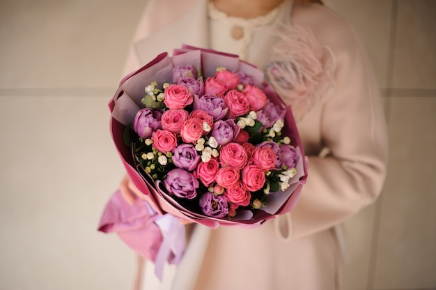 Kobieta w płaszczu z bukietem fioletowych fioletowych i różowych kwiatów