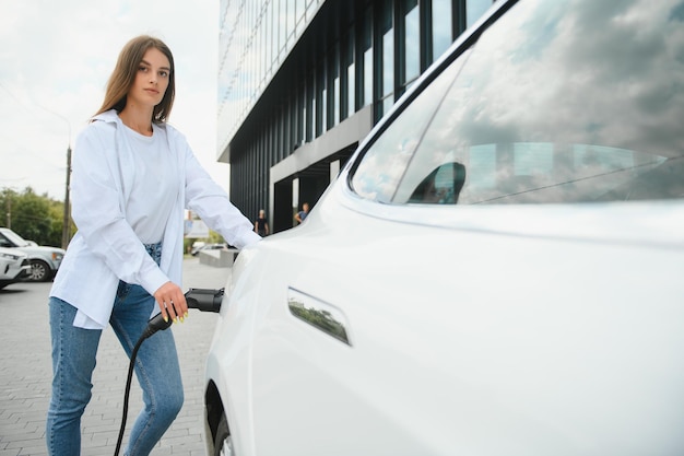 Kobieta W Pobliżu Samochodu Elektrycznego Pojazd ładowany Na Stacji ładującej