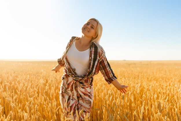 Kobieta w polu pszenicy na tle zachodzącego słońca