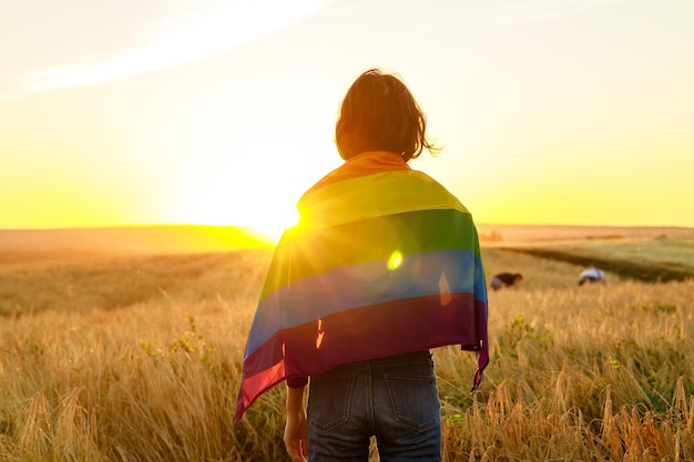 Kobieta W Polu Trzyma Tęczową Flagę Lgbt W Złotym Zachodzie Słońca Wieczorem