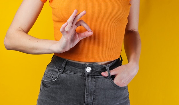 Zdjęcie kobieta w pomarańczowym topie i dżinsach robi ok gest