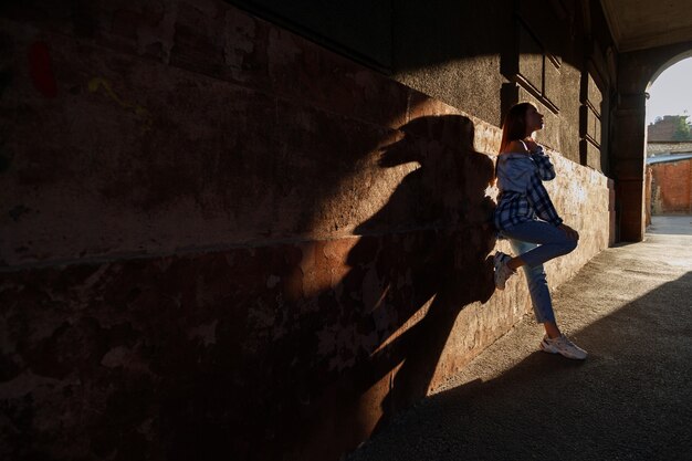 Kobieta w promieniach słońca w mieście miejskiego stylu. sylwetka kobiet w łuku miejskim