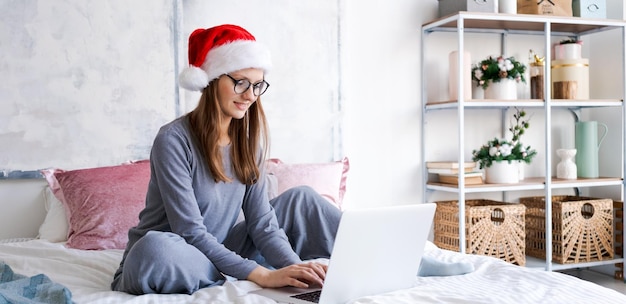 Kobieta w santa hat bawi się na laptopie podczas świątecznych zakupów online na święta