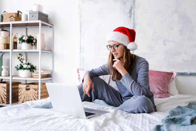 Kobieta w santa hat bawi się na laptopie podczas świątecznych zakupów online na święta