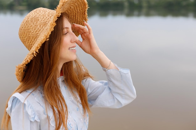 Kobieta w słomkowym kapeluszu uśmiecha się w letnim wolnym miejscu na tekst