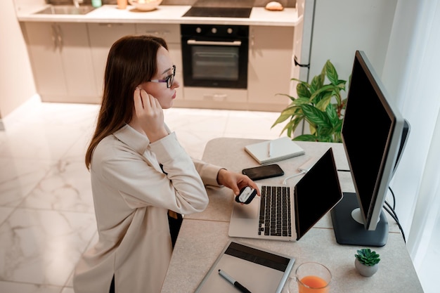 Kobieta w słuchawkach, ubrana w zwykłe ubrania, pracująca w domowym biurze na laptopie Młoda szczęśliwa studentka studiująca na uniwersytecie online