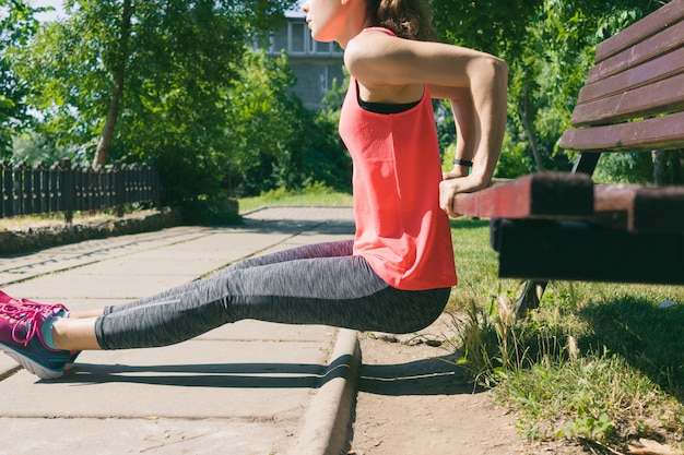 Zdjęcie kobieta w sportowej robi ćwiczenia na triceps na ławce w parku