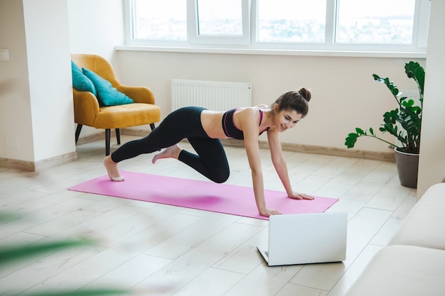 Kobieta W Sportowym Ubraniu W Domu Korzysta Z Laptopa Kobieta Online Rozciąga Się I ćwiczy Jogę Fitness...