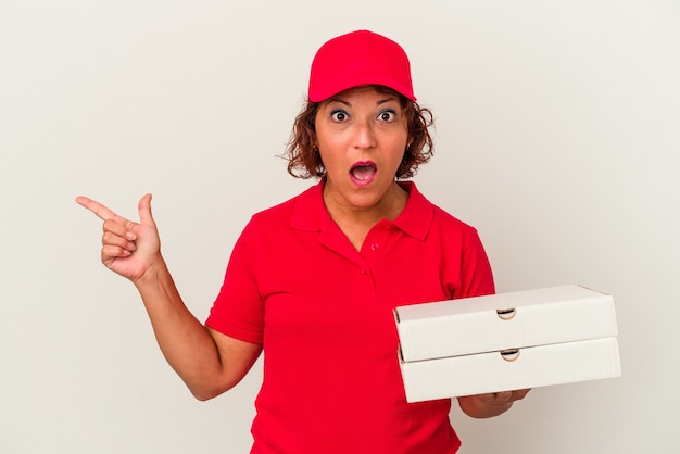 Kobieta w średnim wieku dostarczająca pizze na białym tle wskazująca na bok