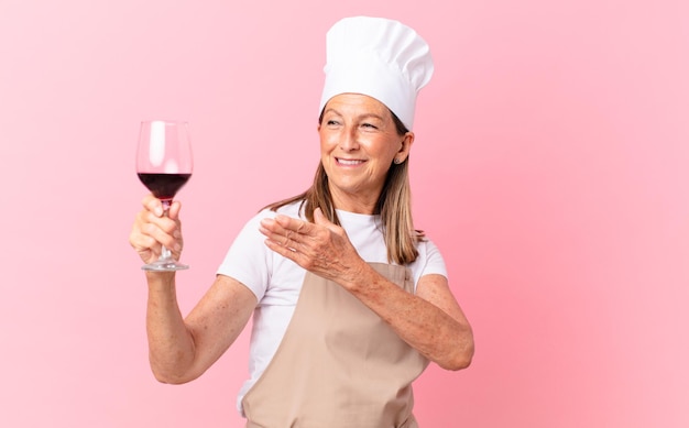Kobieta w średnim wieku, ładna szefowa kuchni z kieliszkiem wina