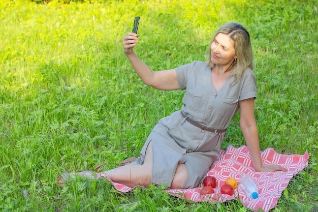 Kobieta w średnim wieku robi selfie w parku latem