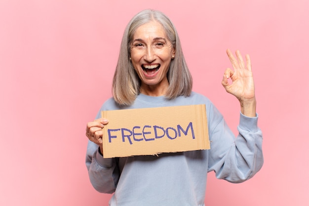 Kobieta w średnim wieku trzyma tablicę wolności