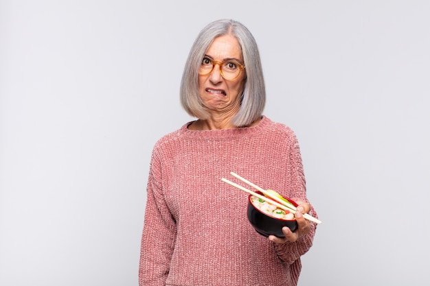 Kobieta w średnim wieku wyglądająca na zdziwioną i zdezorientowaną, przygryzająca wargę nerwowym gestem, nie znająca odpowiedzi na problem azjatyckiej koncepcji jedzenia
