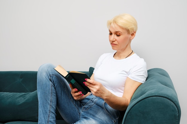 Kobieta w średnim wieku z krótkimi blond włosami czytająca książkę