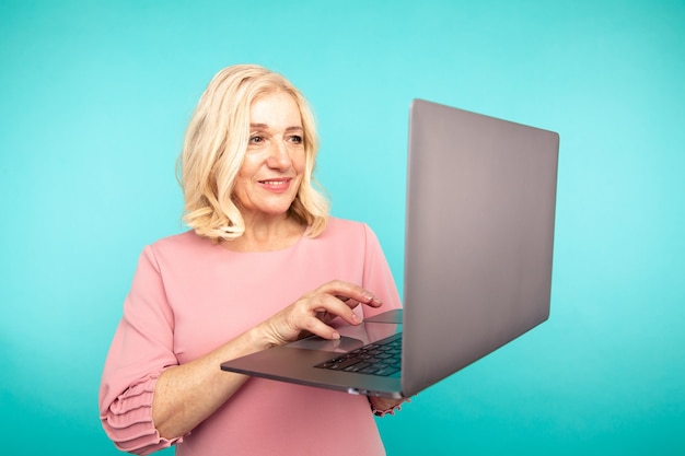 Kobieta w średnim wieku z laptopem na białym tle sprawdzić pocztę i pisać na maszynie.