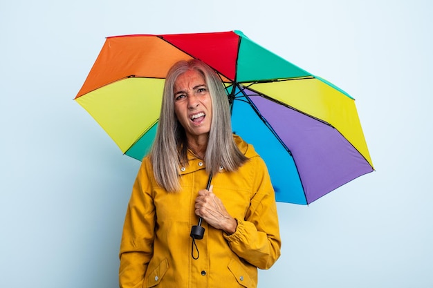 Kobieta w średnim wieku z siwymi włosami czuje się zakłopotana i zdezorientowana. koncepcja parasola i deszczu