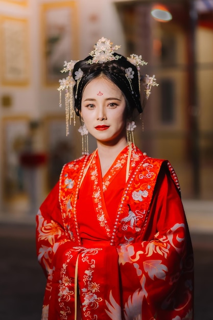 Kobieta w sukience chińskiej Nowy rok portret kobiety w tradycyjnym stroju kobieta w tradycyjnym kostiumie Piękna młoda kobieta w jaskrawo czerwonej sukience i koronie chińskiej królowej pozującej