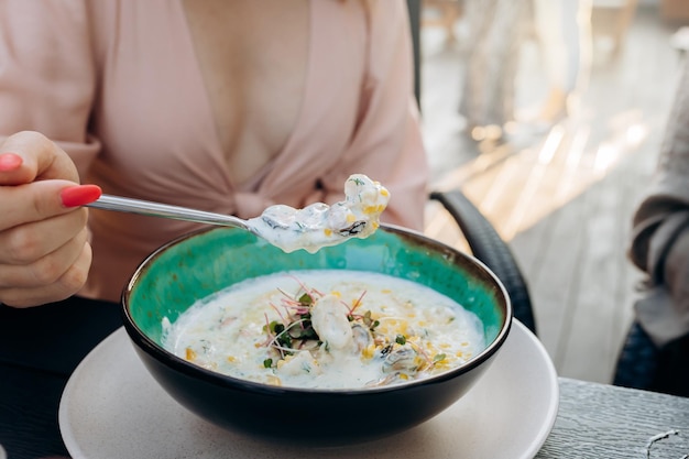 Kobieta w sukience jedząca lunch z małżami w kremowym sosie i różanym winem siedząca na targu spożywczym