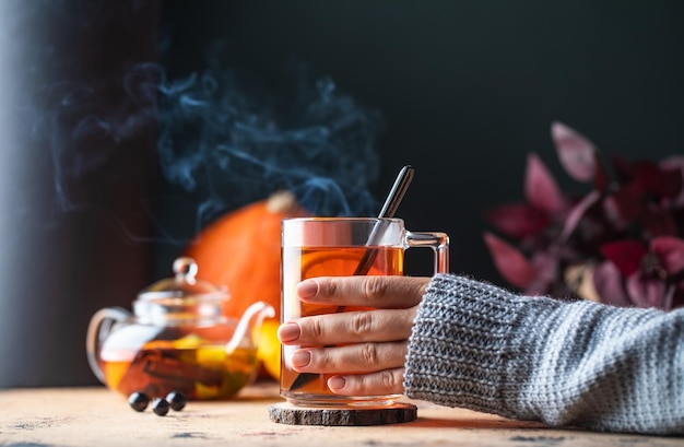 Zdjęcie kobieta w swetrze trzyma kubek gorącej herbaty z cytryną jesienią