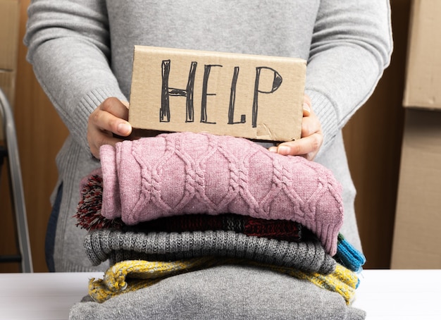 Zdjęcie kobieta w szarym swetrze zbiera ubrania w pudełku, koncepcję pomocy i wolontariatu