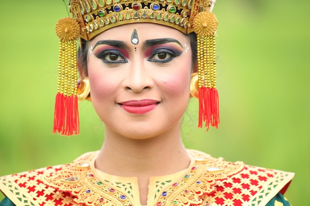 Kobieta w tradycyjnym stroju ze złotym nakryciem głowy i czerwonym topem.