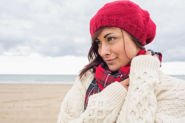 Kobieta w trykotowym kapeluszu i pulowerze na plaży
