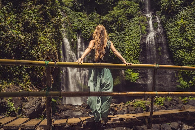 Kobieta w turkusowej sukience przy wodospadach Sekumpul w dżungli na wyspie Bali Indonezja Bali Travel Concept