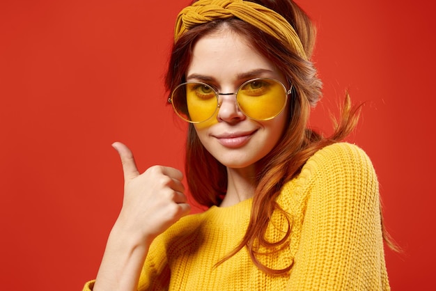 Kobieta w żółtych okularach z bandażem na głowie żółty sweter Hipster czerwone tło Zdjęcie wysokiej jakości