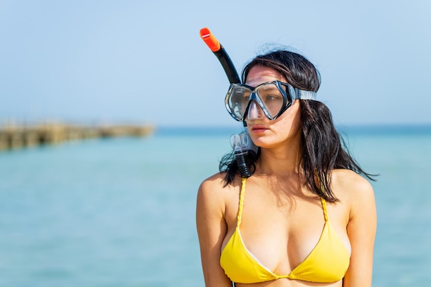 Kobieta w żółtym bikini i akwalung zbierająca plastikowe śmieci z morza