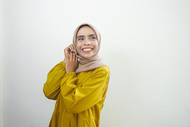 Kobieta w żółtym hidżabie rozmawia przez telefon komórkowy.