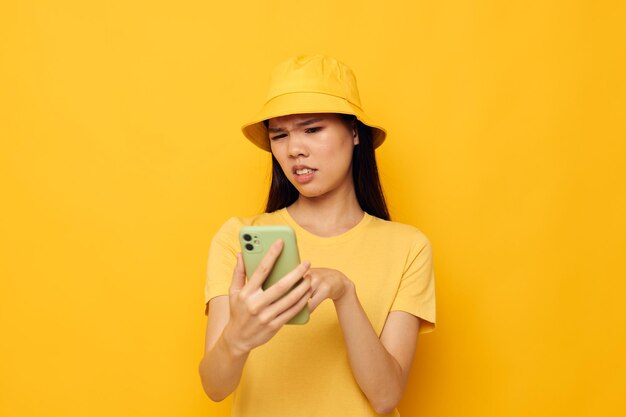 Kobieta w żółtym kapeluszu i koszulce rozmawia przez telefon żółte tło niezmienione