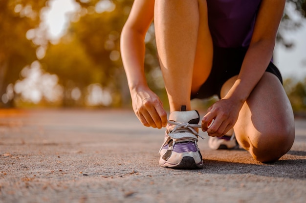 Kobieta wiązanie sznurowadeł do butów przygotowuje się do biegu. Kobieta jogger przygotowuje się do biegania na świeżym powietrzu po drodze. Bieganie na świeżym powietrzu w lesie.