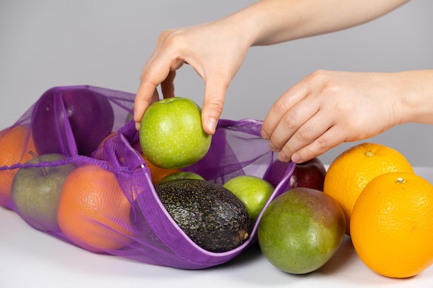 Kobieta wkłada owoce do sieci Koncepcja porzucania plastikowych toreb na zakupy