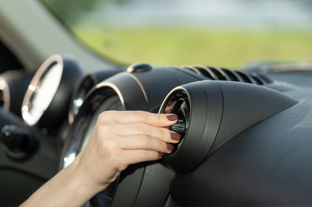 Kobieta włącza klimatyzator w samochodzie w układzie chłodzenia siatki panelu pojazdu Klimatyzacja samochodowa