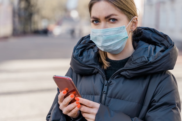 kobieta włożyła maskę, aby chronić się przed wirusem covid-19 za pomocą smartfona