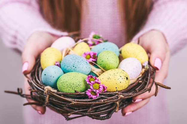 Kobieta wręcza mienie malującego Easter jajko w małym gniazdeczku