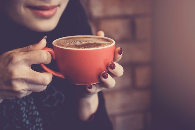 Kobieta wręcza mieniu czerwonego filiżanki kawy latte