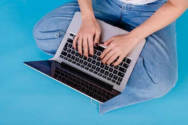 Kobieta wręcza pisać na maszynie na laptopie na błękicie