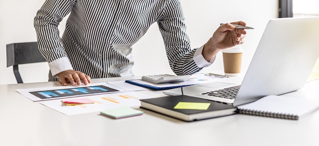 Kobieta Wskazująca Na Ekran Laptopa I Dokumenty Leżące Na Stole, Biznesowa Kobieta W Czarnym Garniturze Siedzi Sprawdzając Informacje Z Dokumentów, Jest Dyrektorem Firmy. Koncepcja Zarządzania Firmą