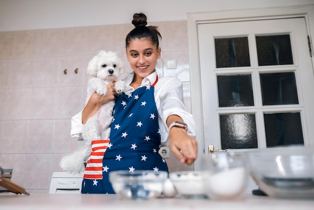 Zdjęcie kobieta wskazująca palcem w kuchni trzymając maltańskiego psa