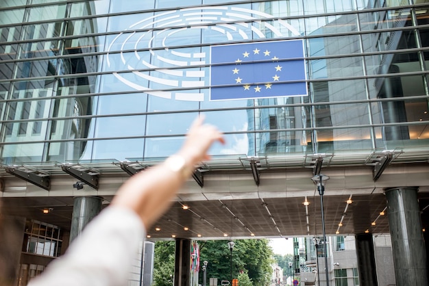 Zdjęcie kobieta wskazująca ręką na fladze europejskiej na budynku parlamentu w brukseli